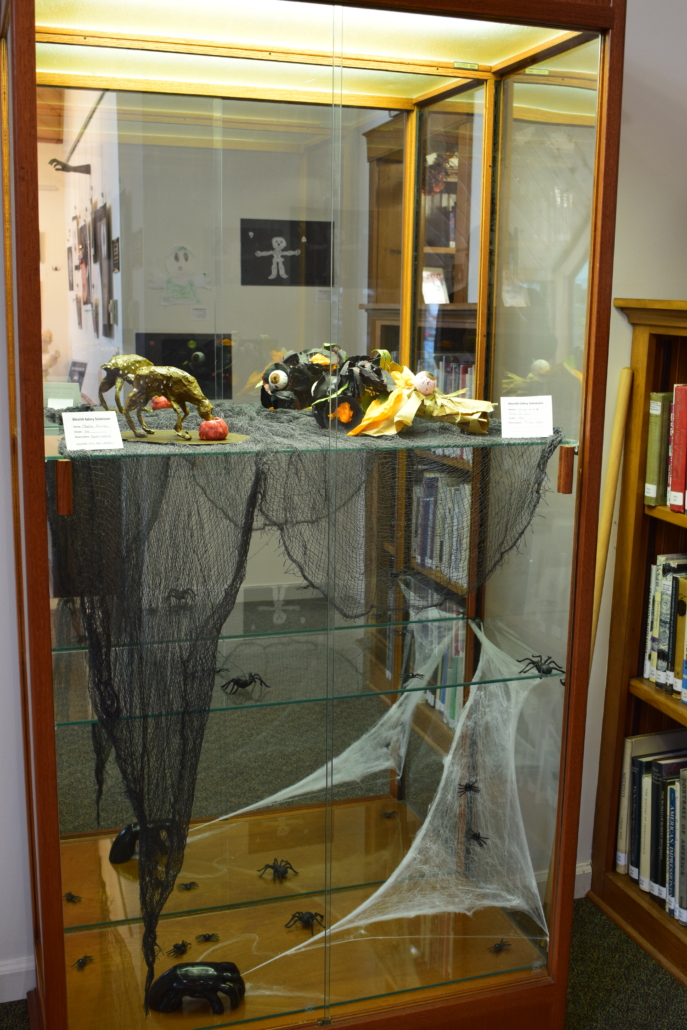 A glass display cabinet full of horror art