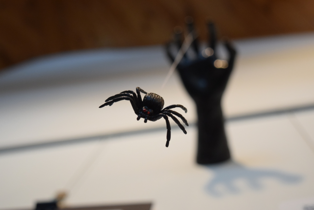 A fake spider hanging on a string from a black-clawed hand